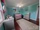 Bedroom with teal walls, gray crib, and decorative flowers at 327 Johnson Dairy Rd, Mooresville, NC 28115