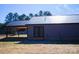 Rear view of home showcasing gray metal siding, black metal roof, and double doors at 411 E Gary St, Candor, NC 27229