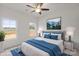 Stylishly staged bedroom featuring soft gray headboard, a ceiling fan, and large, bright windows at 8078 Blackwood Rd, Denver, NC 28037