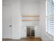 Built in beverage center with a mini-fridge, wood shelving, and accent lighting by a window at 2534 Park Rose Ln # 11, Charlotte, NC 28204