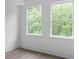 Bright bedroom with hardwood floors and two large windows offering a view of the lush greenery outside at 2538 Park Rose Ln # 10, Charlotte, NC 28204