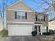Two-story house with beige siding, white garage door, and landscaping at 11627 Tribal Dr, Charlotte, NC 28214