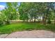 Large backyard with mature trees, lush greenery, and a wrought iron fence creating a private outdoor space at 2607 White Pines Ct, Monroe, NC 28112