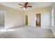 An empty bedroom featuring neutral paint, trim, carpet, ceiling fan, and multiple doorways and windows at 2607 White Pines Ct, Monroe, NC 28112