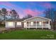 Charming single-story home with a welcoming front porch, well-maintained lawn, and colorful dusk sky at 443 Picadilly Ln, Troutman, NC 28166