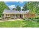 Charming ranch-style home featuring a welcoming front porch, lush lawn, and manicured landscaping at 7135 Folger Dr, Charlotte, NC 28270