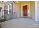 Front porch with dark red door and black metal railing at 900 Raffaelo Vw, Mount Holly, NC 28120