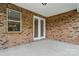 Covered brick patio with a window and glass double doors providing a serene outdoor living space at 9657 Liberty Hill Dr, Mint Hill, NC 28227