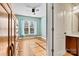 Light-filled bedroom with hardwood floors, a ceiling fan, and views of an attached bathroom at 103 Glenholden Ln, Mooresville, NC 28115