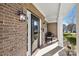 Inviting front porch with brick facade, black door, and wicker chairs at 114 Runningdeer Dr, Mooresville, NC 28117