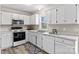 White kitchen features stainless steel appliances and wood-look flooring at 116 Westover Ave, Kannapolis, NC 28081