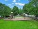 Community playground with swings and slides, surrounded by lush green grass at 11615 Kingsley View Dr, Charlotte, NC 28277