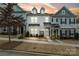 Three-story townhome with gray and white siding, a green door, and stone accents at dusk at 12515 Bryton Ridge Pkwy, Huntersville, NC 28078