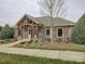 Community clubhouse featuring a stone facade, arched windows, and a well-maintained lawn with colorful flowerbeds at 1255 Restoration Dr, Waxhaw, NC 28173