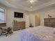 Main bedroom featuring a tray ceiling, carpet, tv, lots of windows and access to the en-suite bathroom at 1255 Restoration Dr, Waxhaw, NC 28173