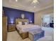 Main bedroom featuring a tray ceiling, en-suite bathroom, blue accent wall and upholstered storage bench at 1255 Restoration Dr, Waxhaw, NC 28173