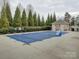 Community swimming pool with a protective cover, surrounded by trees and a fence for privacy and safety at 1255 Restoration Dr, Waxhaw, NC 28173