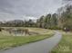 Scenic walking path winding alongside a pond with a fountain, providing a peaceful outdoor recreation space at 1255 Restoration Dr, Waxhaw, NC 28173