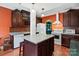 Kitchen with dark brown cabinets, an island, and orange walls at 5915 Quail Hollow Rd # E, Charlotte, NC 28210