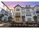 Three-story townhome with gray and white exterior, brick accents, and a charming front porch at sunset at 6027 Towering Oaks Dr, Charlotte, NC 28205