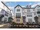 Modern three-story townhome with gray and white exterior, brick accents, and a charming front porch at 6027 Towering Oaks Dr, Charlotte, NC 28205