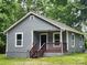 Gray house with brown porch and steps, surrounded by lush green trees at 1302 Brookdale St, Kannapolis, NC 28083