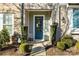 Front entrance of townhome with teal door, landscaping, and walkway at 7520 Waverly Walk Ave, Charlotte, NC 28277