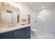 Modern bathroom with blue vanity, white quartz countertop, and glass shower at 1214 S Kings Dr # A, Charlotte, NC 28207