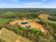 Sprawling aerial view of the property including a house, pond, turf field and picturesque surroundings at 1565 Shinnville Rd, Cleveland, NC 27013