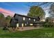 Rear exterior of black home showcasing a patio with stone flooring, well-maintained lawn and outdoor space at 1565 Shinnville Rd, Cleveland, NC 27013