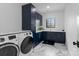 Functional laundry room with navy cabinets, modern appliances and stylish tile floor at 1565 Shinnville Rd, Cleveland, NC 27013