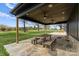 Covered patio with stone flooring features a large picnic table and ceiling fans, perfect for outdoor entertaining at 1565 Shinnville Rd, Cleveland, NC 27013