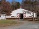 White barn with red accents and double doors; inviting equestrian space at 172 Tuckertown Rd, New London, NC 28127