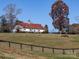Horse grazes in pasture with barn in background; idyllic rural setting at 172 Tuckertown Rd, New London, NC 28127