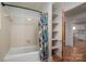 Traditional bathroom featuring a white tub and tiled walls with a shower curtain with tropical leaf patterns and storage shelves at 2073 Mauney Rd, Bessemer City, NC 28016