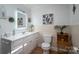 Bright bathroom featuring a white vanity with drawers and cabinets, wood floors, a toilet, and fun, tropical decor at 2073 Mauney Rd, Bessemer City, NC 28016