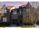 Charming two-story townhouse with a brick exterior, attached garage, and manicured landscaping against a twilight sky at 6411 Aldworth Ln, Charlotte, NC 28226
