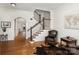 Inviting foyer with hardwood floors, staircase, archway, sitting area with leather chair and stylish decor elements at 6411 Aldworth Ln, Charlotte, NC 28226