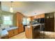 Well-lit kitchen with wood cabinets, breakfast bar seating, and black appliances at 2407 Brookside Ave, Kannapolis, NC 28081