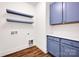 Bright laundry room featuring custom blue cabinets, stylish wood flooring, and floating shelves for optimal storage at 425 Delburg Mill Alley Dr, Davidson, NC 28036