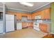 Galley kitchen with light wood cabinets and white appliances at 5435 Village Nw Dr, Concord, NC 28027