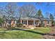 Brick ranch home with a covered porch, steps, and a well-manicured lawn at 6511 Newhall Rd, Charlotte, NC 28270