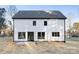 Rear view of a modern farmhouse showcasing white siding, black windows, and a patio at 10605 S Hampton Dr, Charlotte, NC 28227