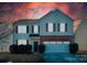 Two-story house with brick and siding, a two-car garage, and landscaping at dusk at 11906 Bending Branch Rd, Charlotte, NC 28227