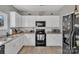 Kitchen with white cabinets, black appliances, and laminate flooring at 11906 Bending Branch Rd, Charlotte, NC 28227