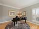 Sitting room with a black piano, hardwood floors, and plantation shutters at 3827 Bramwyck Dr, Charlotte, NC 28210