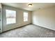 Spacious bedroom with neutral carpet, two windows, and a door at 129 Sharon Rd, York, SC 29745