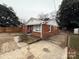 Brick ranch house with a gravel driveway and a wooden fence at 1401 Lasalle St, Charlotte, NC 28216