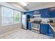 Kitchen features blue cabinets, stainless steel appliances, and tile floor at 182 Water Oak Dr, Pineville, NC 28134