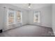 Well-lit bedroom featuring grey carpeting and two windows with white curtains at 5605 Miami Ln, Concord, NC 28025